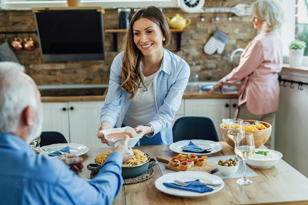 happy-woman-having-lunch-with-her-senior-parents-bringing-food-table-dining-room